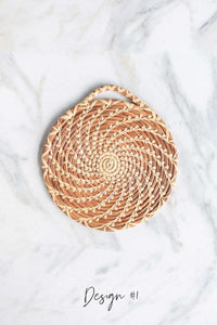 A close up picture of a handmade longleaf pine needle trivet in Design #1 on a white marble background.
