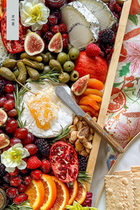 The Bistrot Spreader Knife, In Vintage Teak resting on a cheese and charcuterie board.