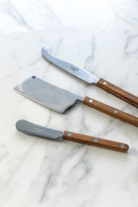 The Bistrot Cheese Knives Set, In Vintage Teak lying on a marble counter.