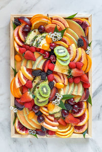 A fresh seasonal fruit platter available for delivery in Vermont, abundant and overflowing with assorted seasonal citrus, melon, berries, kiwi, pineapple, plums, and cherries.