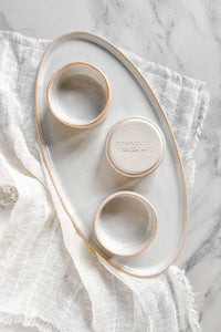 Three stoneware white ramekin dishes with a raw clay edge sitting on a table with a matching serving tray.