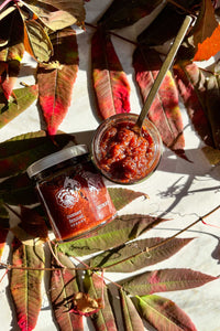 Fall colored leaves and vines are a backdrop for jars of Cherry Fennel Sherry Honey Jam.