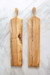 A pair of Spalted Maple bread or cheese boards on a marble counter.